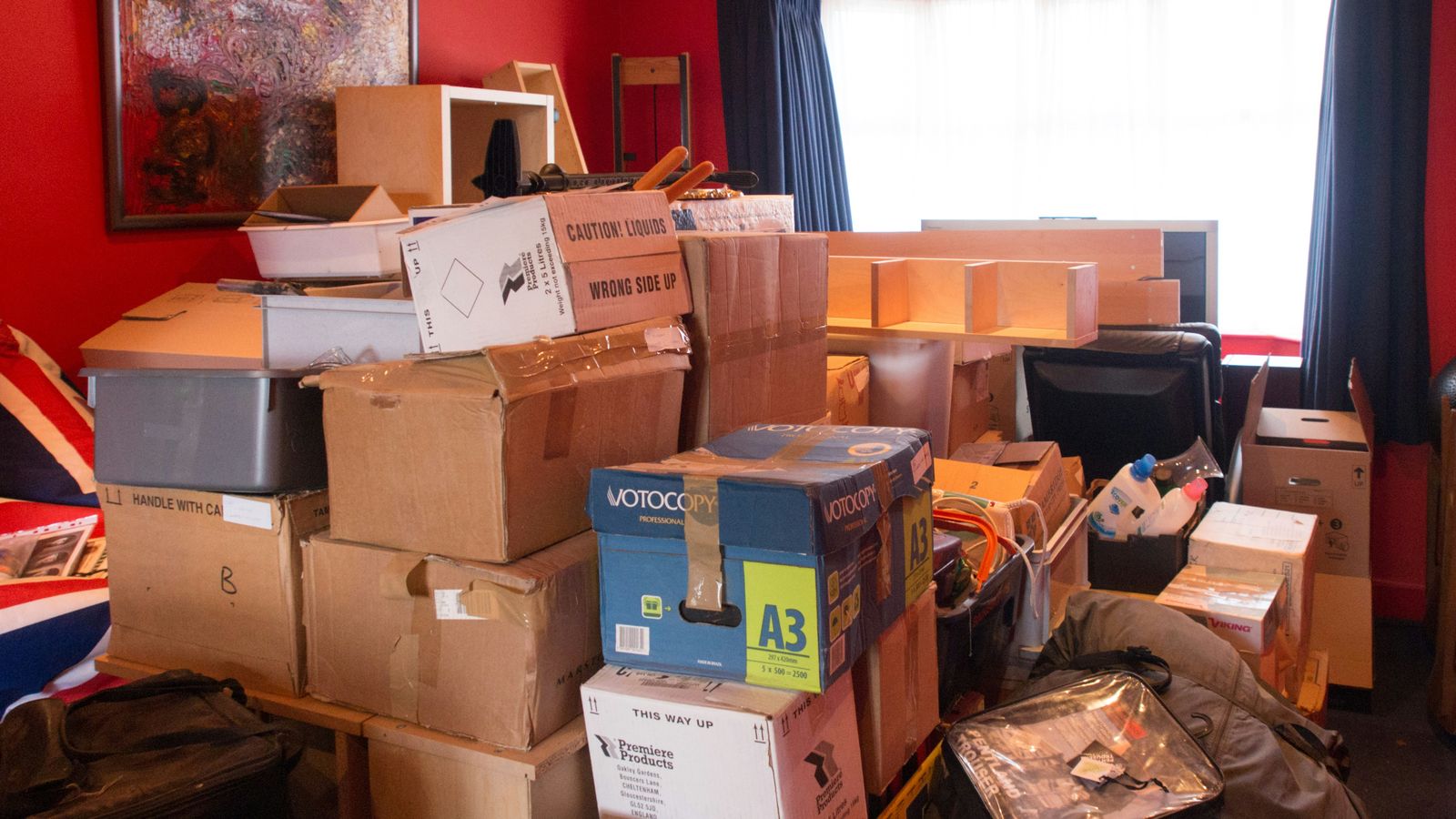 Gestapelte Umzugskartons und Hausrat in einem Zimmer während der Haushaltsauflösung